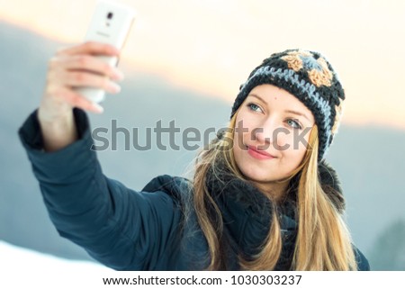 Young woman taking selfie with her smartphone in cold winter day