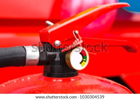 Charged and ready to use fire extinguisher with a manometer. Close-up op a part of a fire extinguisher. The top part of the red powder fire extinguisher.