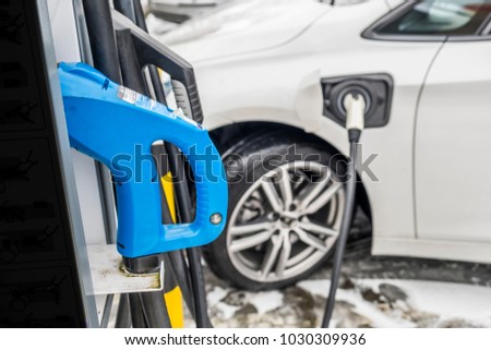 View of an Electric Car Charging and in the background a blurred view of a car Royalty-Free Stock Photo #1030309936