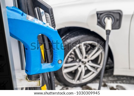 View of an Electric Car Charging and in the background a blurred view of a car Royalty-Free Stock Photo #1030309945