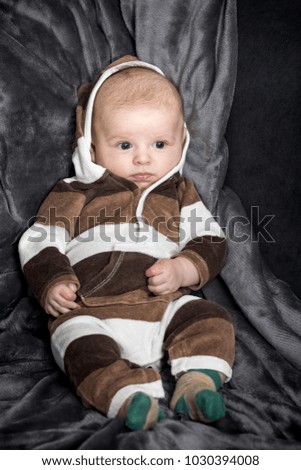 Home photography of a small child in warm clothes with a hood. Natural pictures for home album.