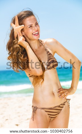 Blue sea, white sand paradise. smiling young woman with long brunette hair in beachwear on the seacoast with starfish having fun time