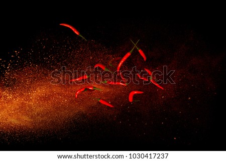Hot red pepper on a background of ground pepper. Flying composition on black background Royalty-Free Stock Photo #1030417237