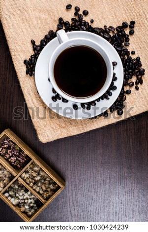 Black coffee in white cup and coffee bean and box on cloth and wood background.