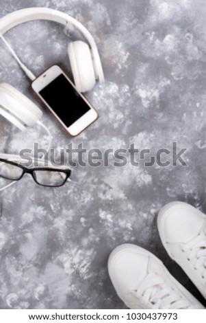 Flat lay Of White Sneakers On stone Background with phone and headphones.