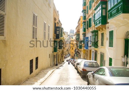 Top view of narrow streets and yellow buildings with colorful balconies and windows in Valletta, Malta