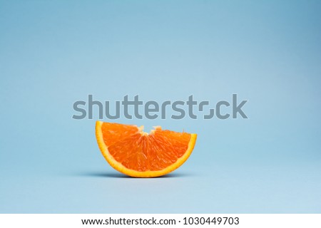 sliced orange fruit isolated on blue background, minimalistic pop art color concept Royalty-Free Stock Photo #1030449703