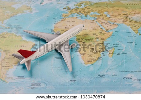 White toy plane on the world map background. Traveling, tourism, international flights with flying airplane model and worldmap, close-up