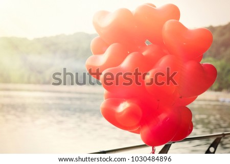 red balloons heart on the waterfront, landscape with bright rays of light. Retro style