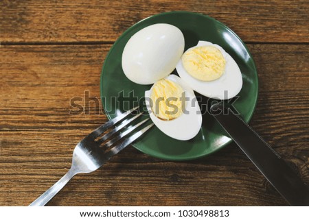 boiled eggs on a green plate. fork and knife. wooden background.