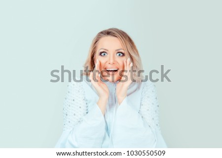 Wow. Close up portrait happy young woman beautiful girl blonde hair looking excited holding her mouth opened hands up on cheeks isolated light green wall. Shocked surprised stunned. Positive emotion