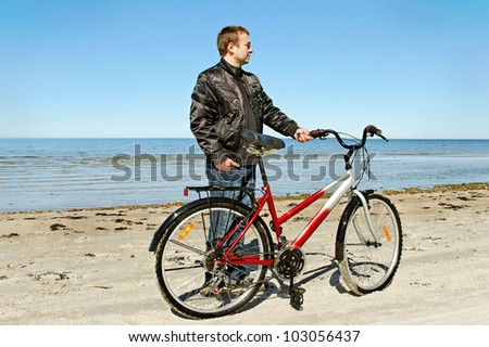 Man with bike on beach of the Baltic sea.