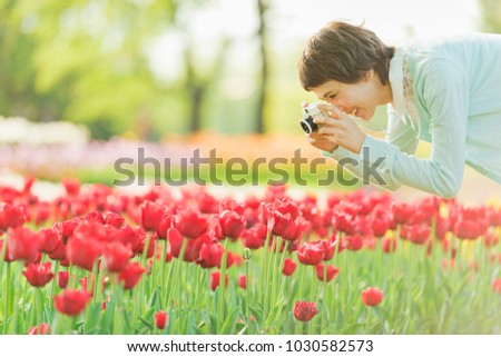 A young woman taking pictures in a flower garden