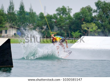 Wake boarding rider jumping trick with water splash in wake park, active sport for healthy ,recreation, hobby, adventure and fun.
                              