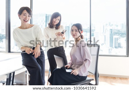 Young women holding various mobile devices. Royalty-Free Stock Photo #1030641592
