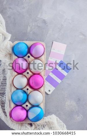 Easter eggs painted in blue and pink shades in a carton with color swatches. Preparing for holidays. Minimalist Easter decorations with copy space.