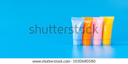 Hygiene products packaging design poster template. Cosmetic tubes on blue background. Yellow orange pink color abstract plastic containers, Copy space photography.
