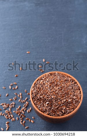 Close-up picture of flax seeds in a clay bowl isolated on dark background.