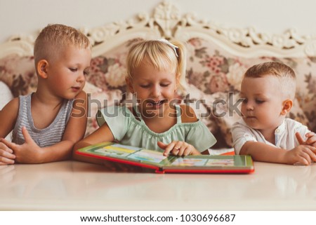 Little Boys and Girl Reading Book at Table at Home