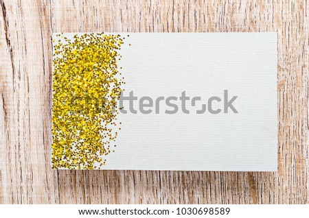 Blank card with gold glitter for your text or message on wooden background.