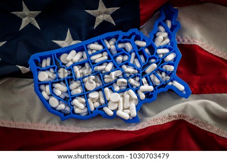 Healthcare, opioid epidemic and drug abuse concept with the map of USA filled with oxycodone and hydrocodone pharmaceutical pills on the American flag Royalty-Free Stock Photo #1030703479