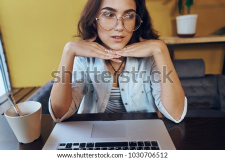  business woman in glasses sits at a table in a cafe with a laptop                              
