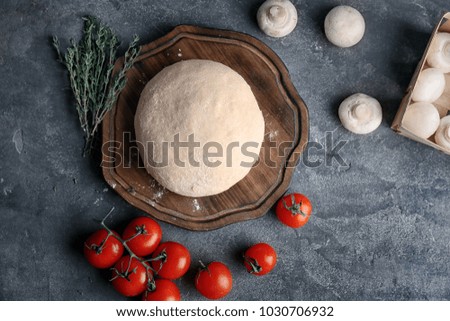 Raw dough with ingredients for pizza on kitchen table