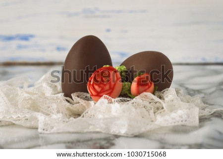 Chocolate Eggs, White Lace Tape, Artificial Decorative Roses on the White Wooden Background. Easter concept.