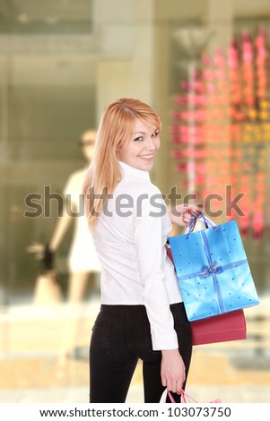 Woman in front of a shop Window with shopping bags