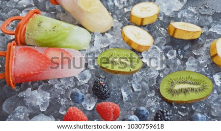Self made popsicles with fruit pieces in it on ice