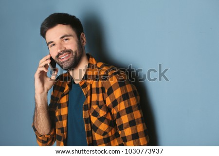 Young man talking on mobile phone against color background