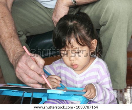 Grandfather teach his granddaughter to drawing