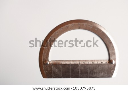 Metallic protractor - tool for mathematics, geometrical drawing, architecture and engineering - on white table background. Engineer, architect business concept top view image with copy space for text.