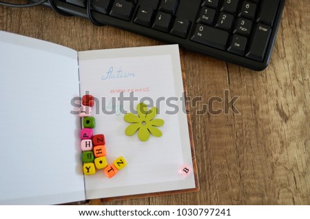 Notebook with phrase "Autism awareness day" with colorful cubes on wooden background