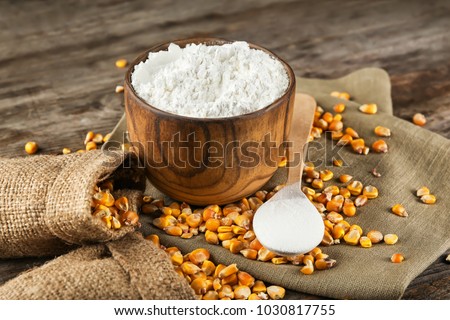 Bowl with corn starch and kernels on table Royalty-Free Stock Photo #1030817755