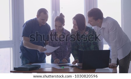 Meeting four elegant people in a stylish office with large panoramic windows at the working place for a signing deal.
