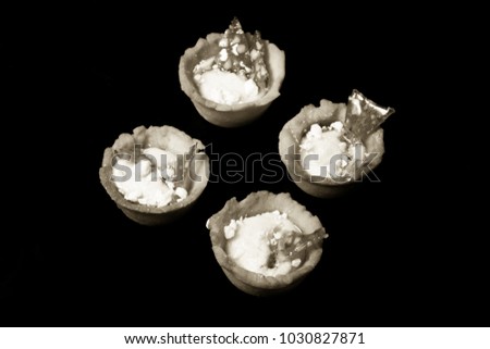 Tartlets with white cream and lemon curd on a black background. Shallow depth of field. Selective focus. Toned.