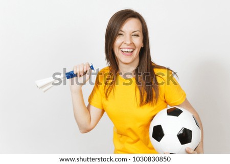 Beautiful European young cheerful happy woman, soccer fan or player in yellow uniform holding football pipe, ball isolated on white background. Sport, play football, health, healthy lifestyle concept