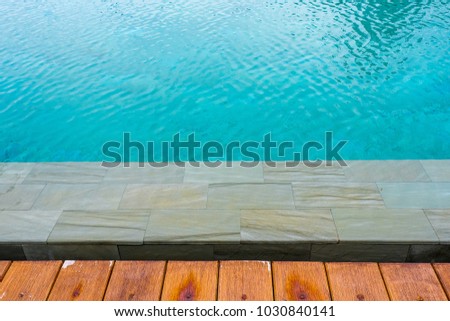 wood texture near swimming pool side. clear blue water in the swimming pool where nobody in it. peaceful clear blue water in swimming pool. wood and pool background 