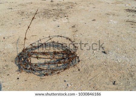 Old rusty barbed wire on cement floor with gravel and garbage background in construction area.