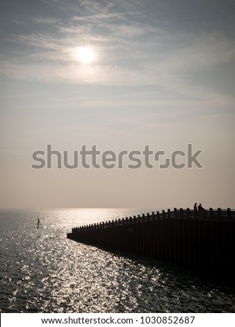 Dusk sea silhouette, Seaford, East Sussex, UK. A dusky view of  the calm waters of the English channel with a foreground pier leading into the sea.