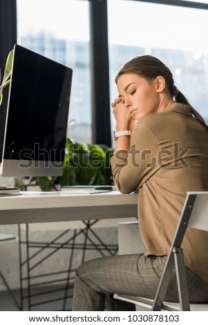 depressed young woman sitting at workplace in office