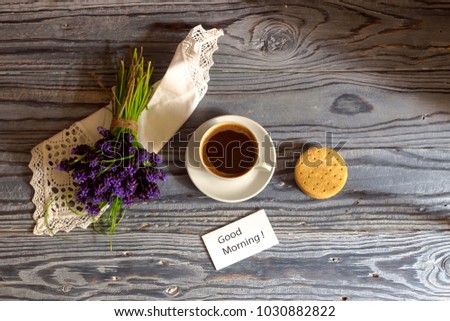 A cup with morning, brewed coffee, biscuits and a romantic bunch of flowers on a wooden table close-up