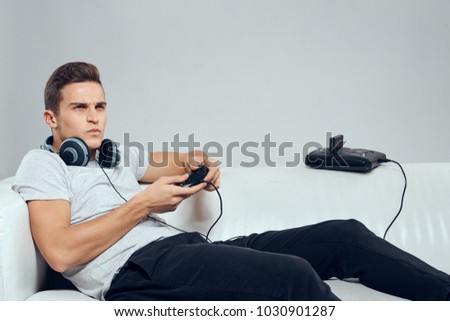 man with headphones on his neck plays in the console on a gray background                              
