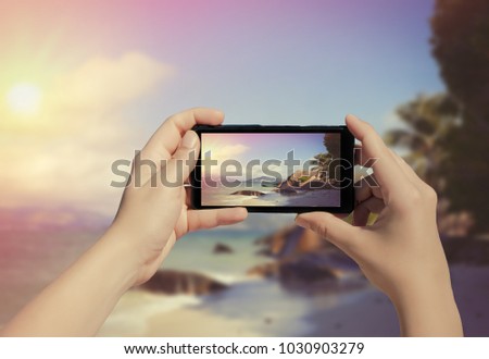 Female hand taking picture of La Digue island on mobile phone. Picture of Seychelles island on smart phone 
