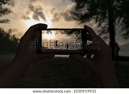 Female hand taking picture of walking people on a rope on the island of La Digue. Seychelles