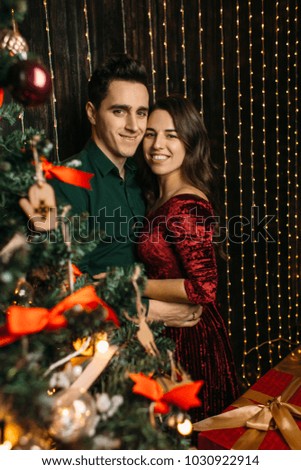 The lovely couple in love embrcing near Christmas Tree