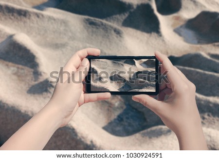 Female hand taking picture of the big stone on La Digue island on mobile phone.  