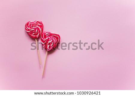 2 red candies in the form of a heart lie one above the other on a purple background