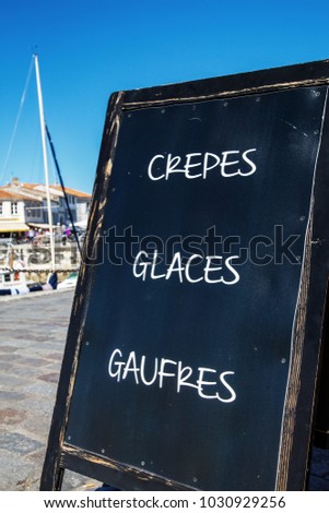 Closeup of sign - "Pancakes, Ice Cream, Waffles" ("Crepes, Glaces, Gaufres" in French) on an harbour